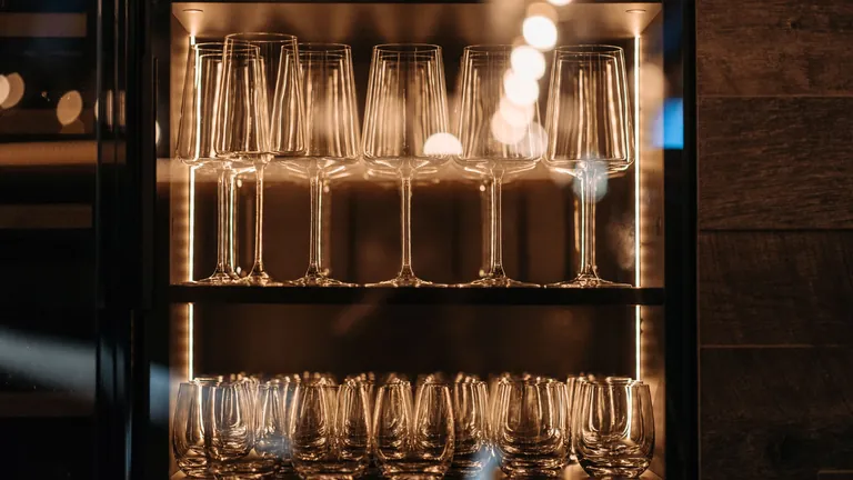 Glass display cabinet with warm internal lighting and glassware